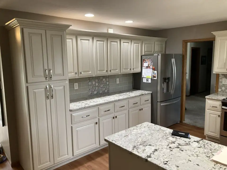 Cream raised-panel kitchen cabinets and a white granite island by Nu-Look Kitchens, a cabinet refacing company in Dubuque, IA