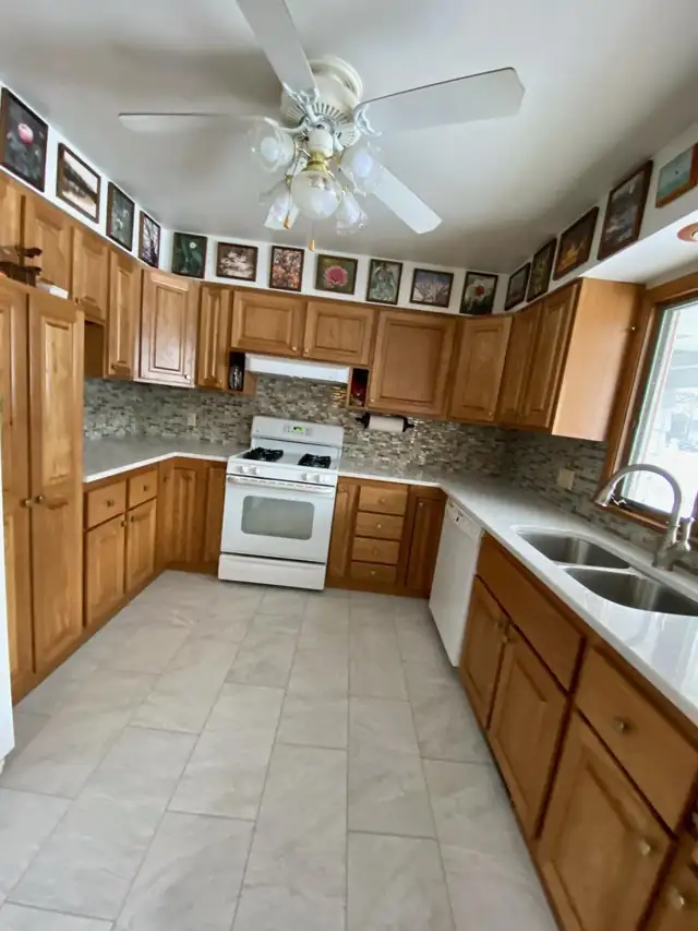 Refaced oak kitchen cabinets with white countertops, a mosaic tile backsplash and a white gas range