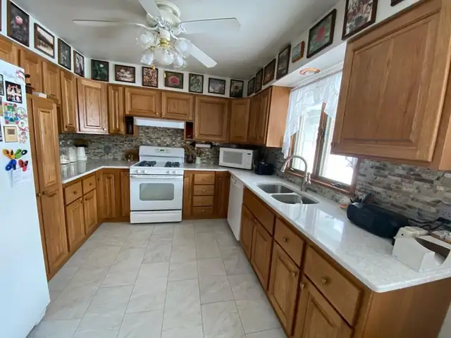 Wide view of refaced oak cabinets with light counters, gas range and tile floor